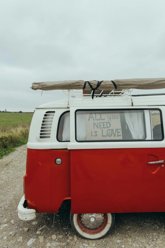 A retro red van parked on a rural road with an inspirational 'All You Need Is Love' message.