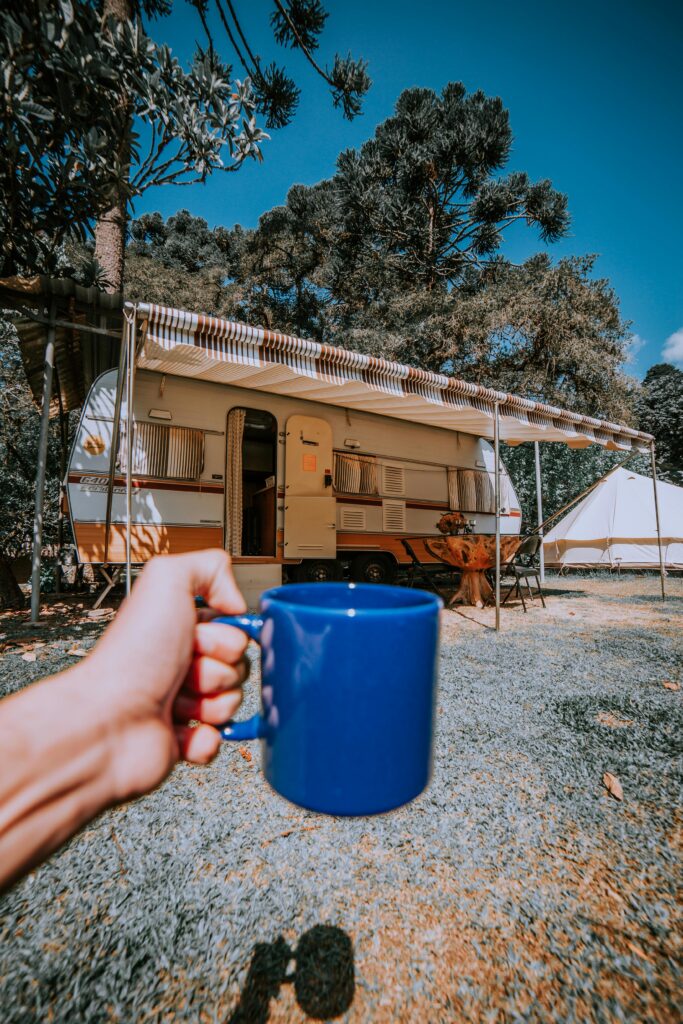 Blue mug held in a pine forest campsite with caravan in Fracalanza, Brazil.